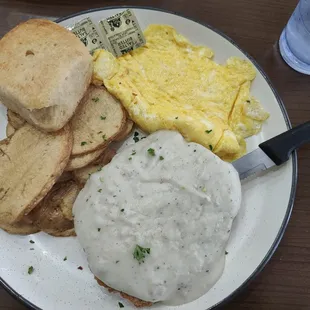 Country fried steak and eggs platter with home fries and biscuit