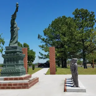 Statues of all branches of services saluting statue of Lady Liberty.