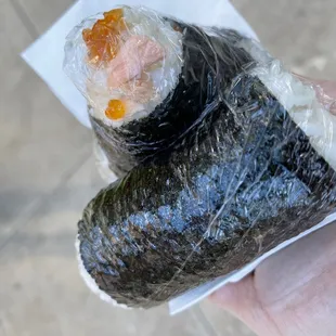 a hand holding a piece of sushi