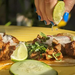 a hand sprinkling a lime over a taco