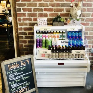 a display of bottles and a sign in front of a brick wall
