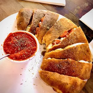 a plate of pizza and a bowl of sauce