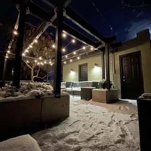 a snow covered patio with string lights