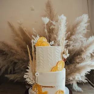 Fresh oranges and pampas grass complete this beautiful wedding cake