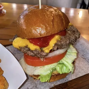 a hamburger with cheese, lettuce and tomato