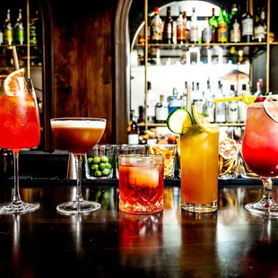 a variety of cocktails on a bar