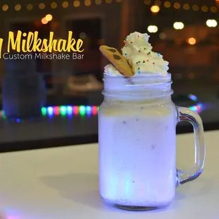 a glass of milkshake with whipped cream and sprinkles