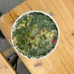 a bowl of spinach on a wooden table