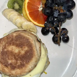 Breakfast sandwich with English muffin, sausage, pepper Jack cheese, fried egg, and fruit side