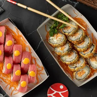 wo plates of sushi and chopsticks