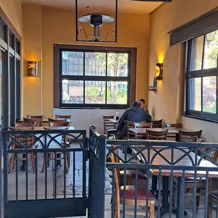 Outdoor covered patio dining has 4 tables for 4 and 1 table for 6 made up of 3 tables for 2.