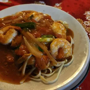 a plate of noodles with shrimp and vegetables