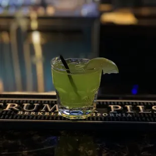 a green cocktail with a slice of lime