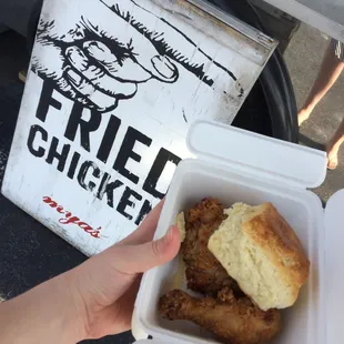 a hand holding a box of fried chicken