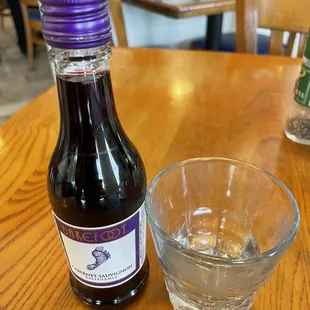a glass of water and a bottle of syrup