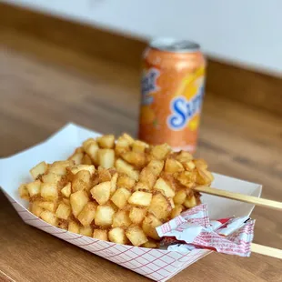 a basket of fried potatoes and a can of soda
