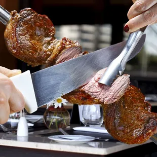 a person cutting a steak with a knife
