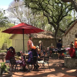 a group of people sitting at tables under an umbrella
