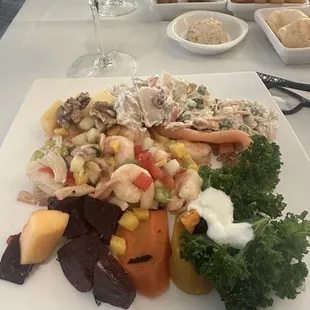 Salad bar plate including beets, potato salad, chicken salad, carrots, walnuts, shrimp and kale .