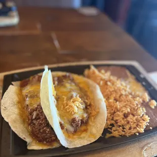 two tacos and rice on a plate