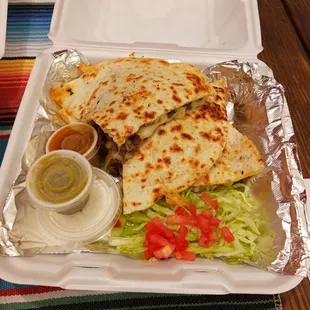 Steak and cheese quesadilla with lettuce, chopped tomato and sour cream.