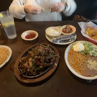 Chicken and steak fajitas with a side order of rice and sour cream.