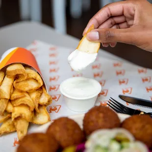 a person dipping a piece of bread into a bowl of dip