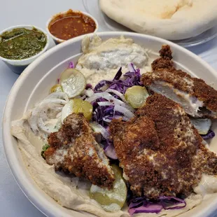 Crispy chicken schnitzel hummus bowl with S'khug and harissa sauces