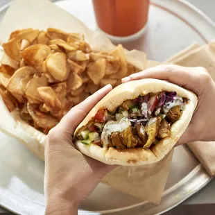 a hand holding a pita sandwich