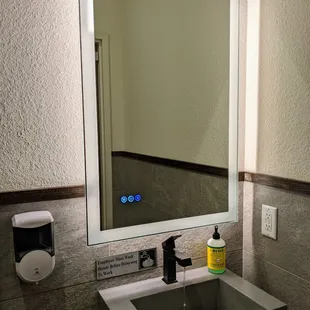 Inside the men&apos;s restroom. Touchscreen light-up mirror and sink.