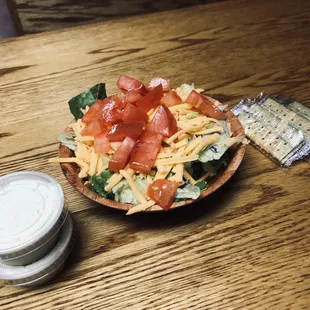a bowl of salad and a bag of chips
