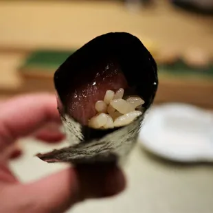 a person holding a piece of sushi