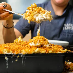 a woman scooping up a serving of macaroni and cheese