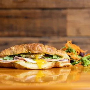 a croissant sandwich on a wooden table