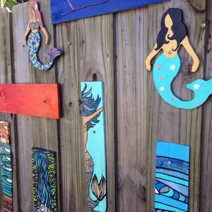 Painted wooden mermaid art in one of the table areas.