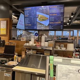 a restaurant counter with a menu on the wall