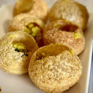 Paani Puri- Crispy hollow puri balls, stuffed with a mixture of potatoes, onions served with mouth-watering spicy water. Vegan