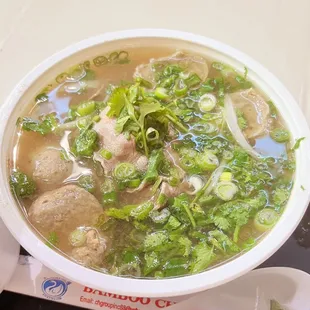 a bowl of soup with meatballs and greens