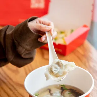 a person holding a spoon full of soup