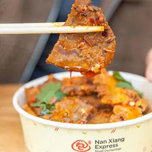 a person holding chopsticks above a bowl of food