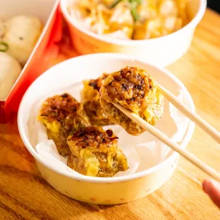a person holding chopsticks over a bowl of food