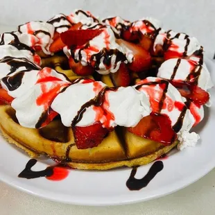 a waffle with whipped cream, strawberries, and chocolate