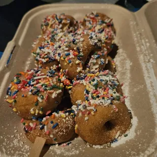 a tray of mini doughnuts with sprinkles