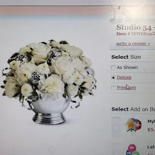 A mix of fresh white flowers such as roses, carnations and button spray chrysanthemums  accented by miniature disco balls &amp; silver ribbons