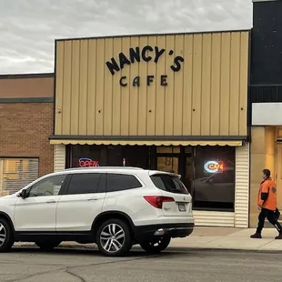 a white suv parked in front of a cafe