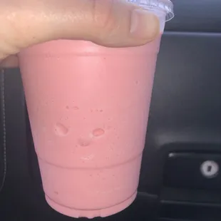 a hand holding a pink drink