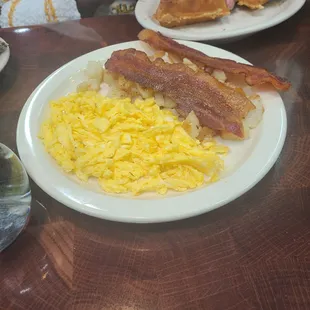 a plate of eggs, bacon and pancakes