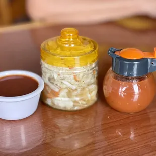 a cup of hot sauce next to a jar of sauerkraut