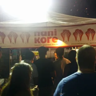 a crowd of people standing under a tent