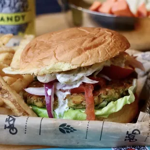 Falafel Burger! Featuring a crispy chickpea falafel burger, cucumber yogurt sauce, onion, lettuce, and tomato, on fluffy potato roll.
